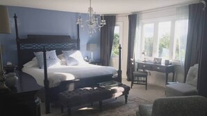 Une chambre à coucher avec un lit à baldaquin, un lustre, un bureau et une chaise.