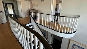 Ein mehrstöckiger Innenraum mit einer Holztreppe und weißen Geländern.