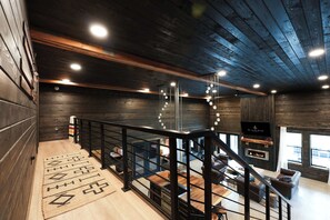 A modern interior with a wooden staircase, a fireplace, and a seating area. - Luxe Nordic Barndominium Retreat at Black Pine (Chattaroy)