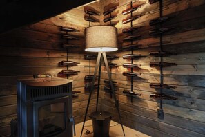 Een kamer met houten lambrisering, een vloerlamp en een wijnrek met flessen.