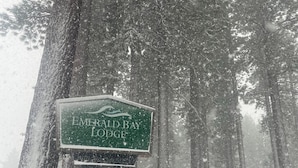 Un panneau indiquant l’emplacement du Emerald Bay Lodge, au milieu d’une forêt enneigée.