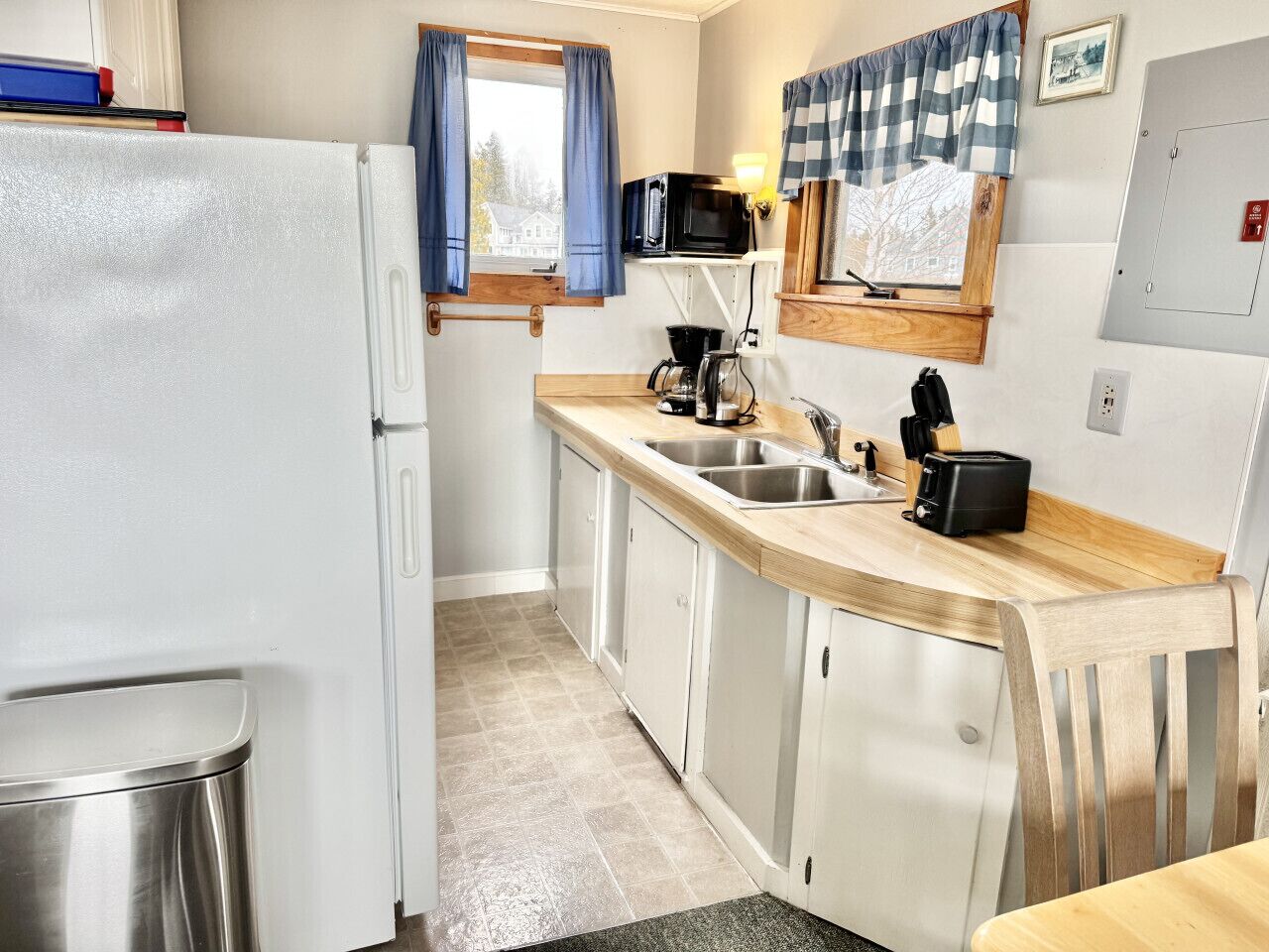 Una cocina compacta equipada con refrigerador, microondas, cafetera y tostadora.