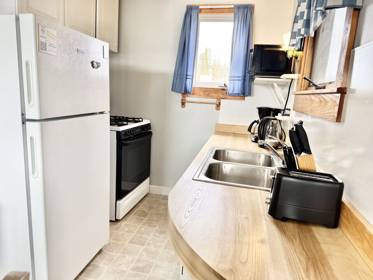 Une cuisine compacte équipée d’un réfrigérateur, d’une cuisinière, d’un évier et d’un grille-pain.