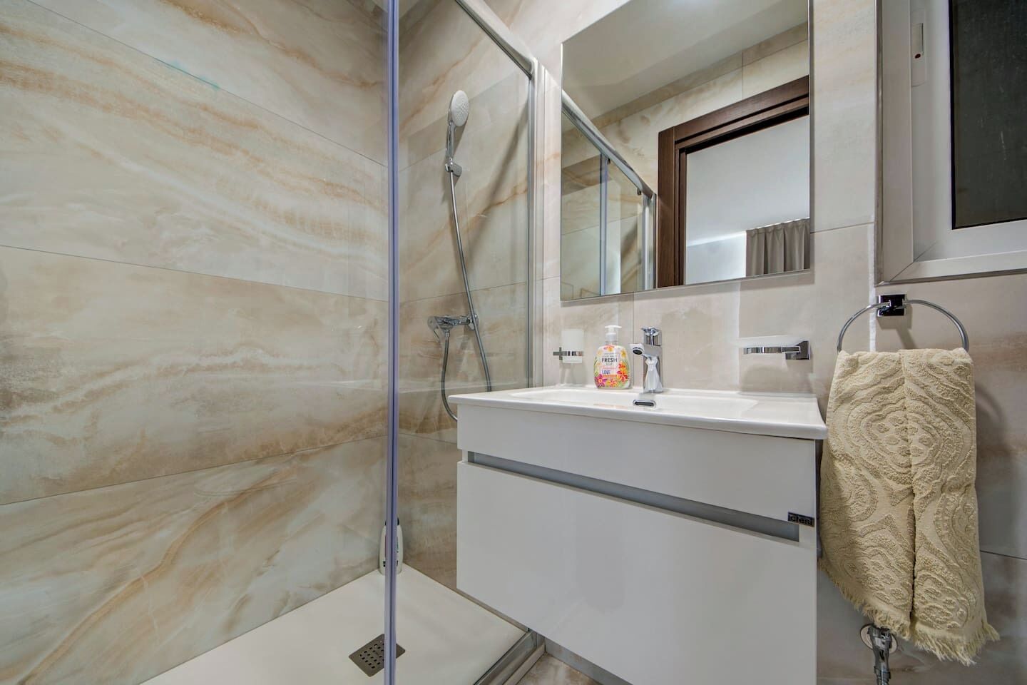 A bathroom with a shower, a sink, and a mirror.