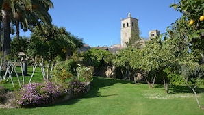 A well-maintained garden with a clear pathway leading to a historic building with a bell tower. - Villa de los Naranjos (Trujillo)