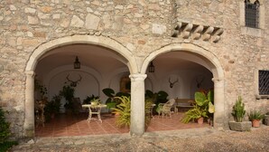 A courtyard with stone walls, arches, and potted plants. - Villa de los Naranjos (Trujillo)