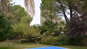 A swimming pool surrounded by lush greenery and a stone wall. - Villa de los Naranjos (Trujillo)