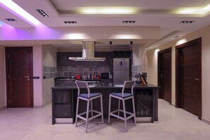A modern kitchen with a central island, bar stools, and built-in appliances. - “5-Star Luxury Apartment Steps from the National Museum of Egyptian Civilization (Cairo Governorate)