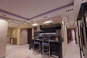 A modern kitchen with a central island, bar stools, and built-in appliances. - “5-Star Luxury Apartment Steps from the National Museum of Egyptian Civilization (Cairo Governorate)