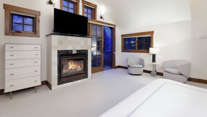 Een moderne slaapkamer met een open haard, een televisie, een bank en een lamp.