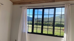 A room with a large window, wooden ceiling, and a bed with a patterned bedspread. - Peaceful Farmhouse • 10 Min to Roldanillo • Perfect for Paragliders (Bolivar)