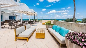 A rooftop bar with outdoor seating, including sofas and tables, overlooking a clear blue sky and ocean. - 1BR Oceanfront Resort with pool (Miami Beach)