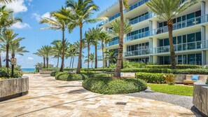 A resort with a paved walkway, palm trees, and a building with balconies. - Beautiful 1/bed apartment (Miami Beach)