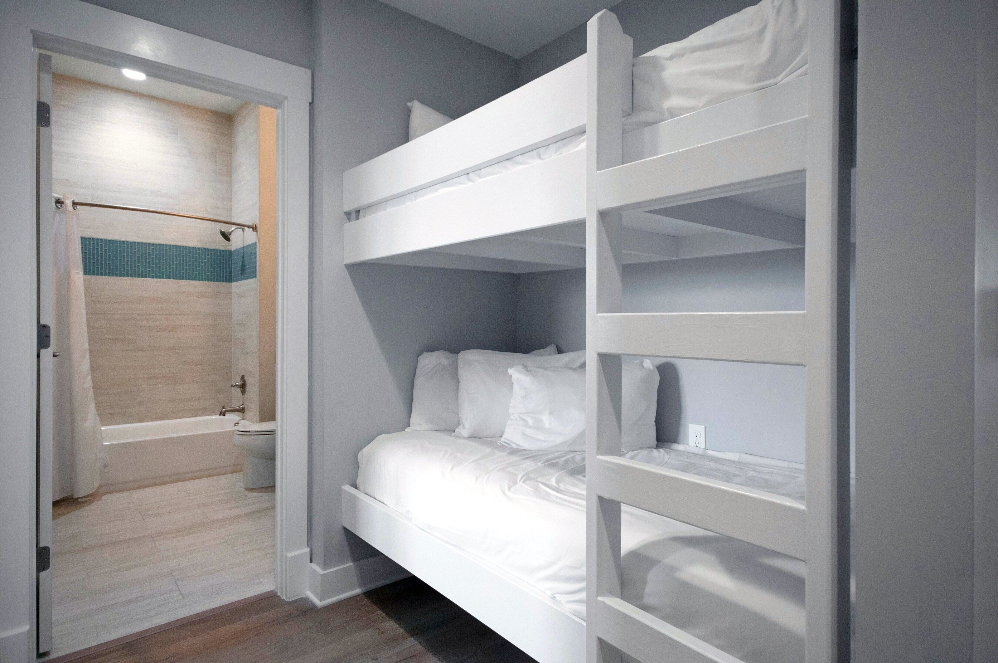 Una stanza con un letto a castello, un angolo doccia e una porta che dà su un'altra stanza.