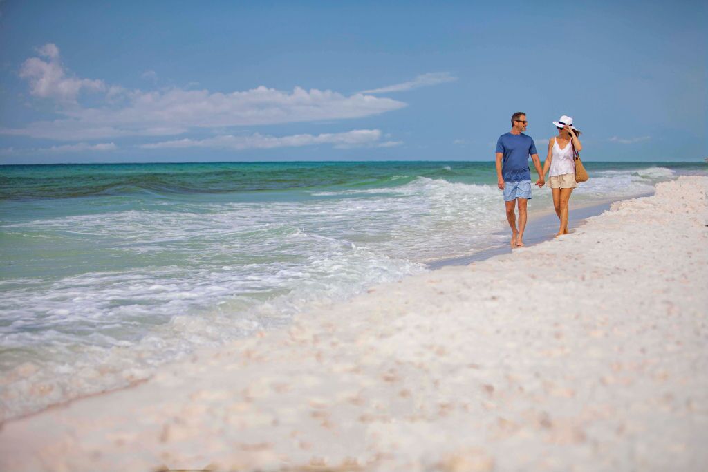 Hand-in-hand moments on a sun-kissed shore, where the waves gently caress the coast.
