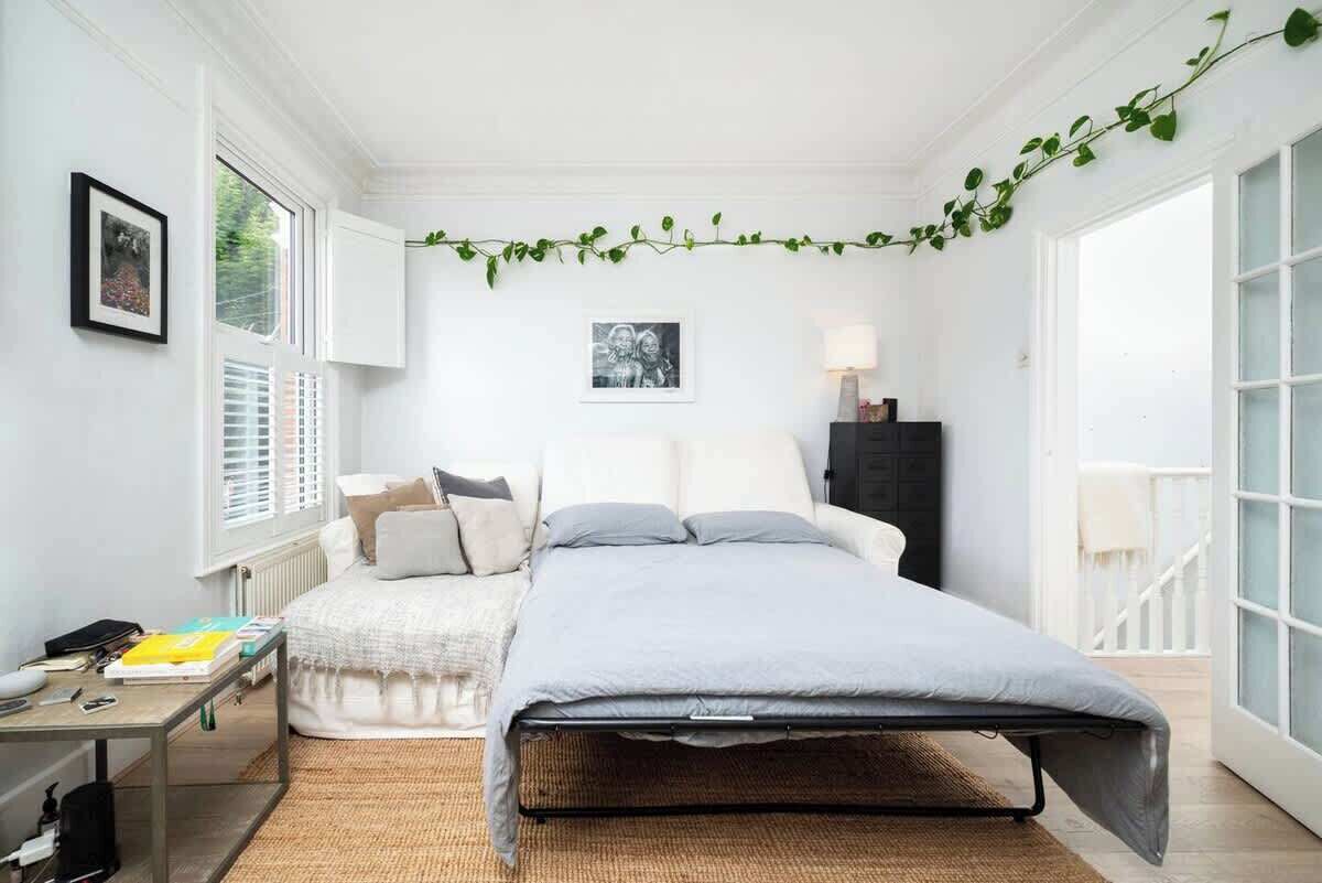 A bedroom with a bed, a bedside table, a lamp, and a window with blinds.