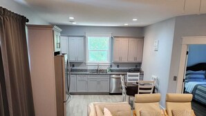 A modern apartment with a kitchenette, a dining area with a sofa and chairs, and a bedroom with a bed. - Beautiful 2-bedroom Apartment above Garage with AC in charming Mount Pleasant (Mount Pleasant)