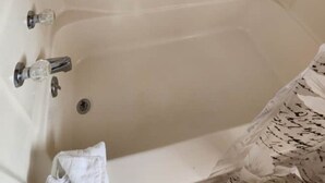 Une baignoire avec deux robinets et un drain.