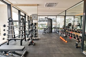 Ein Fitnessstudio mit Kraftgeräten, Laufbändern und Kurzhanteln.