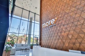 A modern hotel lobby with a reception desk, seating area, and large windows offering views of the outdoors. - Modern 1BR Suite Apartment in Prime Location (Asunción)