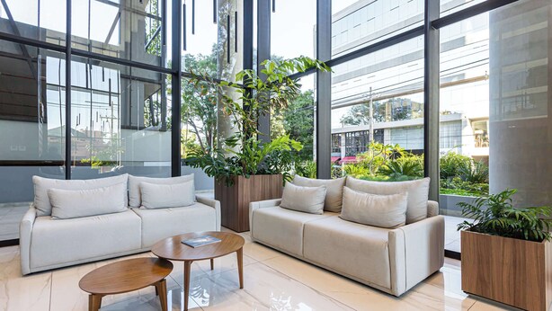 Un salon moderne avec deux canapés, une table basse et de grandes fenêtres offrant une vue sur les bâtiments et la verdure.