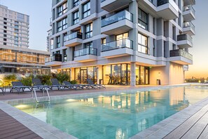 A modern building with a swimming pool, outdoor seating, and a fitness center. - A luxury space 1BR Apartment Suite designed to make you feel at home (Asunción)