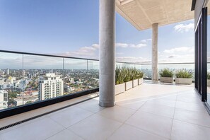 A spacious balcony with a city view, large pillars, and potted plants. - A luxury space 1BR Apartment Suite designed to make you feel at home (Asunción)