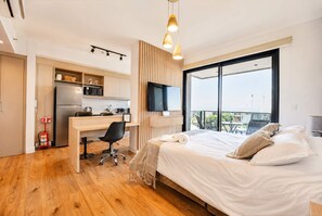 Una habitación de hotel moderna con una cama grande, un escritorio, una televisión y un balcón con vistas.