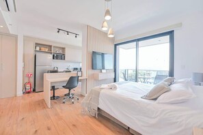 Habitación de hotel moderna con cama, escritorio, silla y televisor.