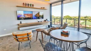A modern room with a large TV, seating area, and a balcony with a view. - A luxury space designed to make you feel at home (Asunción)