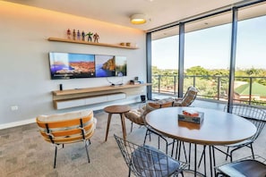 Una habitación moderna con una televisión grande, zona de estar y balcón con vistas.