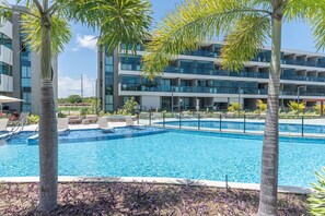 A modern hotel with a swimming pool, lounge chairs, and palm trees. - Beach Class Summer by Carpediem (Ipojuca)