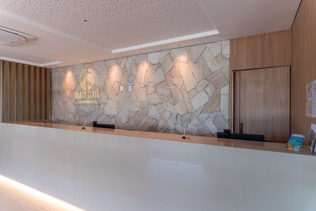 A reception desk with a stone wall backdrop, a logo, and a wooden panel on the right.