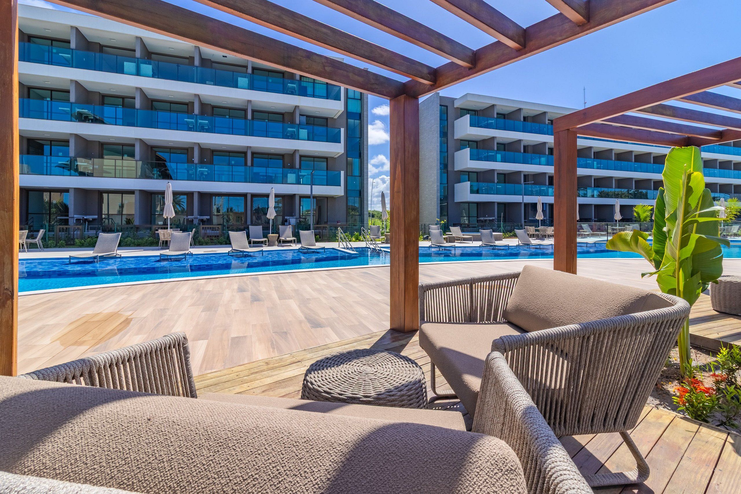 A poolside area with lounge chairs and a view of a modern building with balconies.