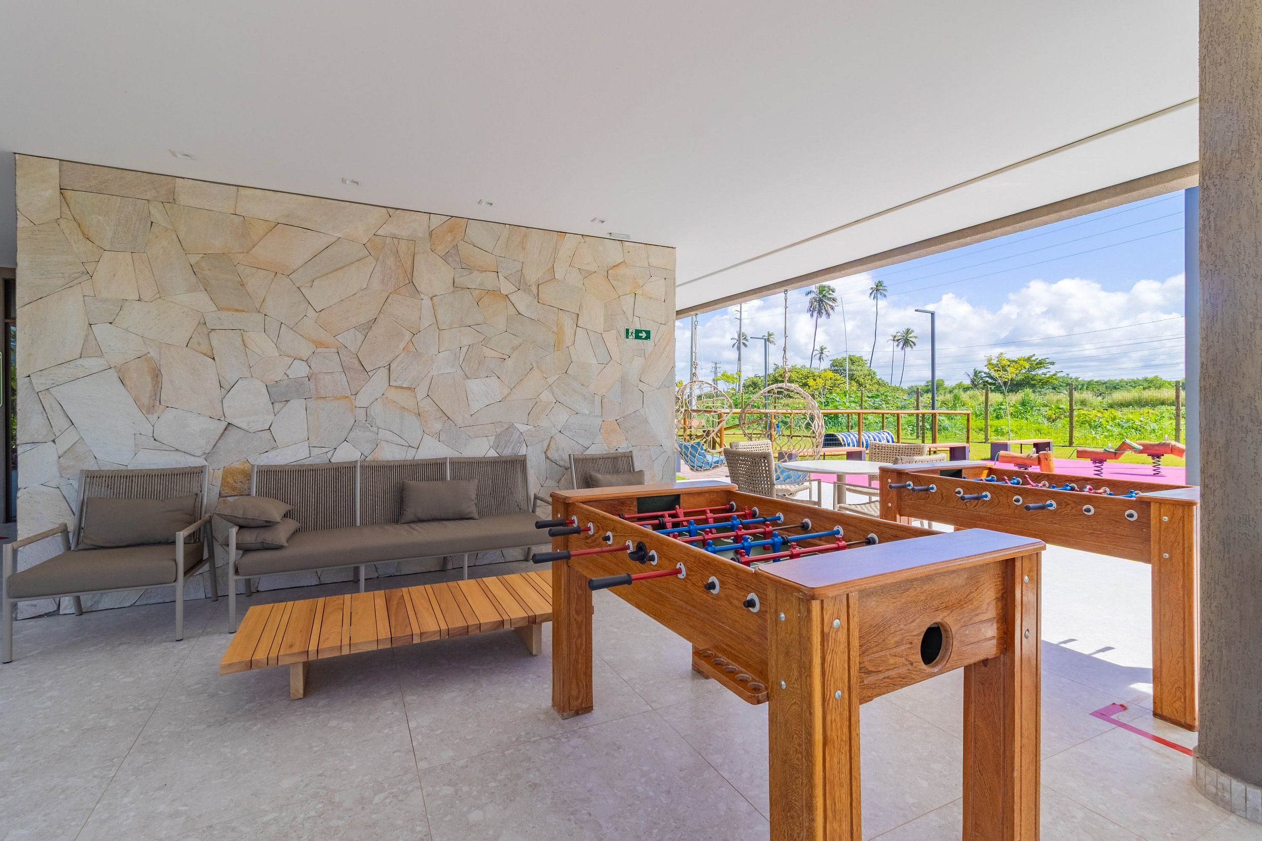A modern indoor area with a stone wall, seating, and a foosball table.