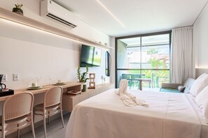 A hotel room with a bed, a desk with chairs, a TV, and a balcony with chairs. - Beach Class Summer by Carpediem (Ipojuca)