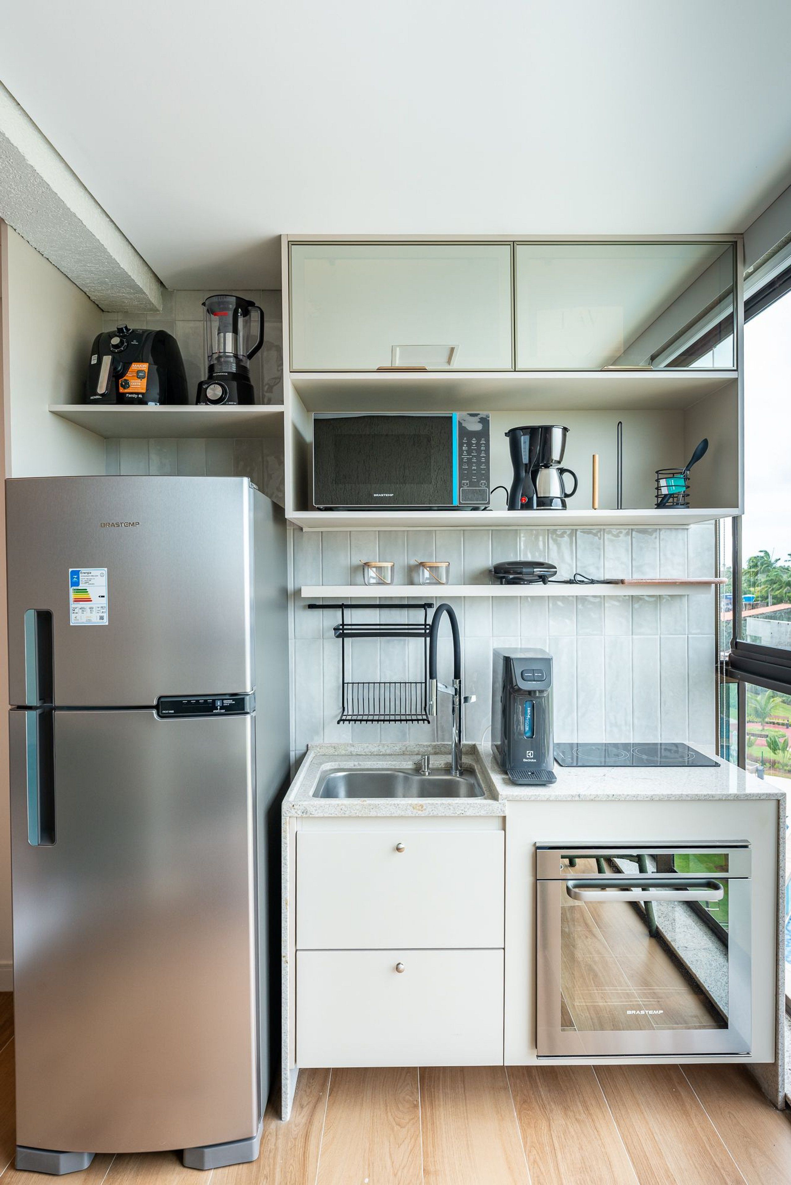 A compact kitchen with a stainless steel refrigerator, a microwave, a coffee maker, and a dishwasher.