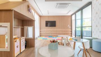 Un moderno cuarto de juegos infantil con armarios de madera, televisor y un amplio ventanal.