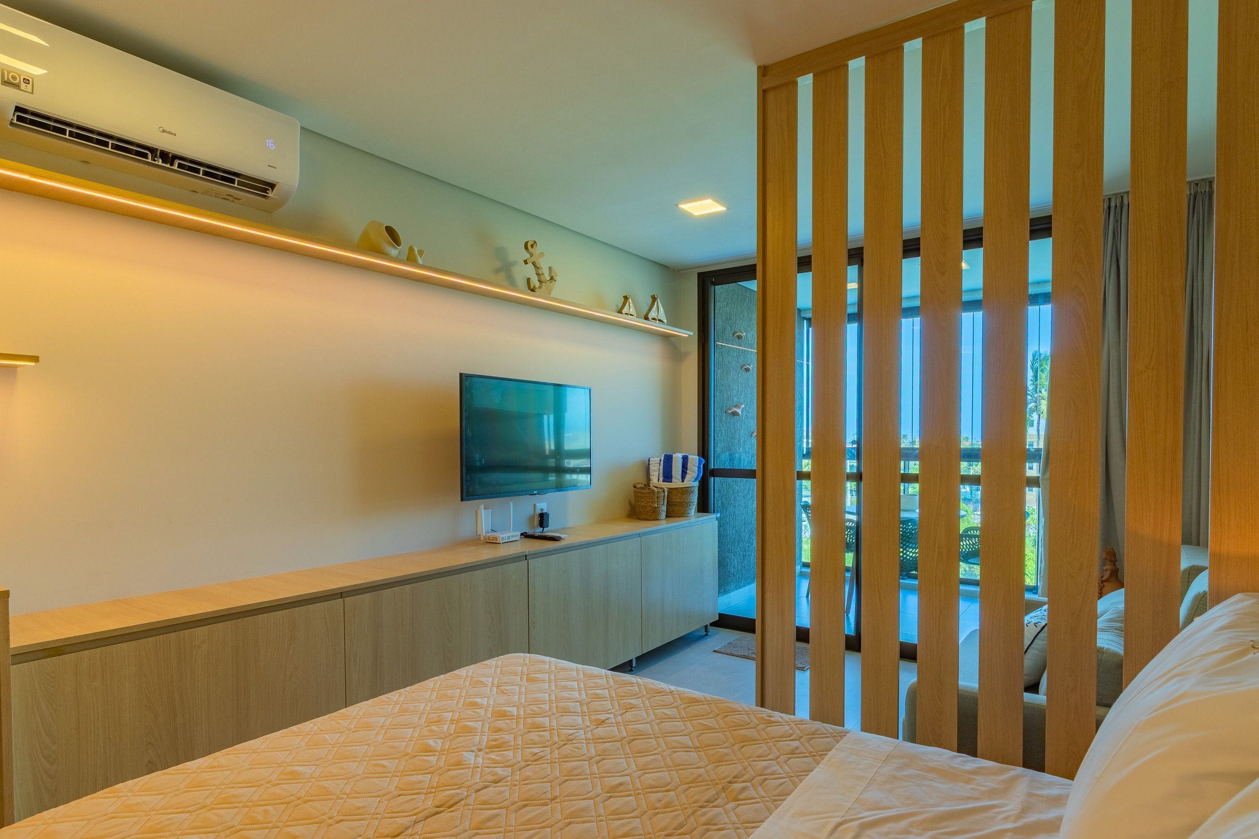 Een hotelkamer met een bed, een televisie, een houten kast en een balkon met uitzicht.