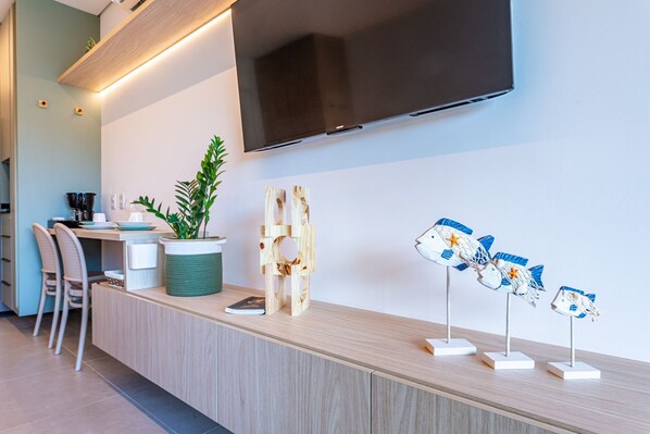 Une cuisine moderne équipée d’un téléviseur à écran plat, de meubles en bois, d’une plante et de sculptures de poissons décoratives.