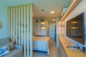 Habitación de hotel con cama, sofá, televisor y escritorio con computadora y control remoto.