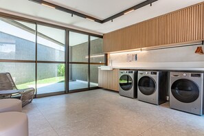 Une buanderie moderne avec de grandes fenêtres, un lave-linge et un plan de travail.