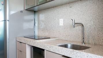 Una cocina moderna con refrigerador de acero inoxidable, encimera de granito y lavavajillas integrado.