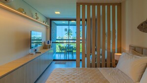 A hotel room with a bed, a TV, a desk, a balcony with a table and chairs, and a sliding door. - Beach Class Summer by Carpediem (Ipojuca)