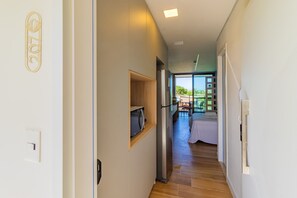 A narrow hallway with a built-in microwave shelf, a stainless steel refrigerator, and a door with a light switch. - Beach Class Summer by Carpediem (Ipojuca)