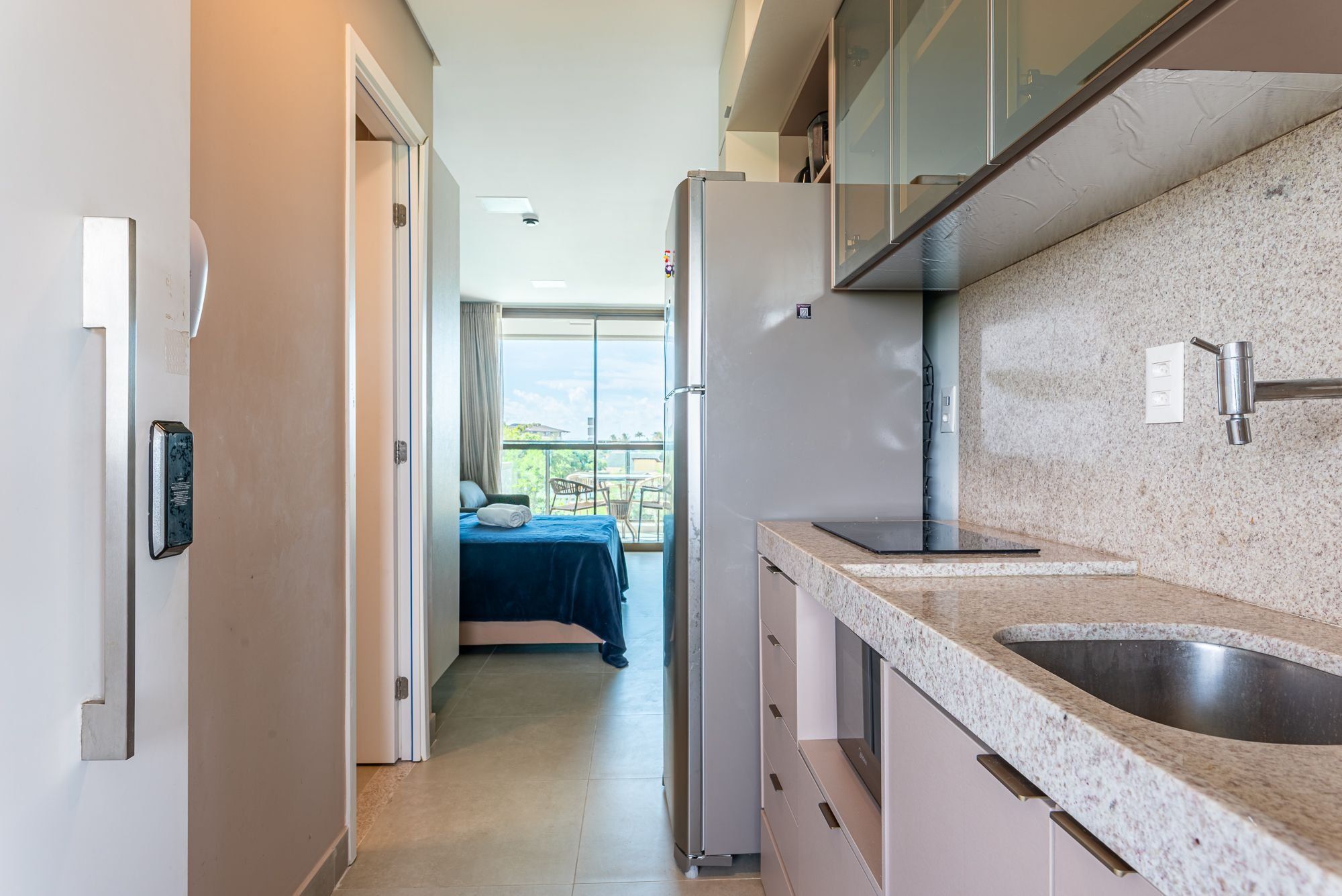A compact kitchen with a granite countertop, a built-in sink, and a refrigerator.