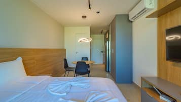 Una habitación de hotel con cama, escritorio, silla, televisor y aire acondicionado.