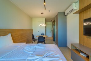 Hotellihuone, jossa on sänky, työpöytä, tuoli, televisio ja ilmastointilaite.
