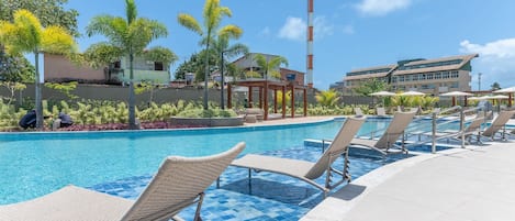 Una piscina con sillas de descanso, un pabellón y una torre de comunicaciones alta al fondo.