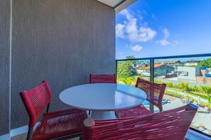 A balcony with a round table and red wicker chairs, overlooking a residential area with houses and greenery. - Beach Class Summer by Carpediem (Ipojuca)